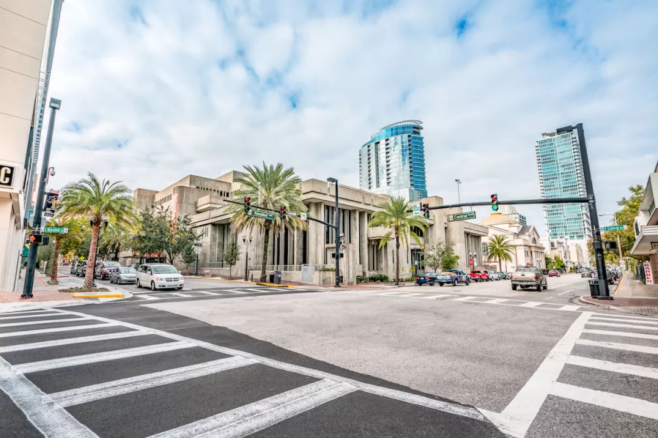 View of empty zebra crosswalk at intersection in Orlando, Florida with glass towers in background.